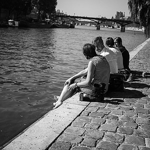 grayscale photography of people sitting beside river thumbnail