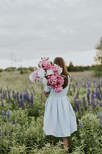 woman walking at garden while holding bouquet of flowers thumbnail