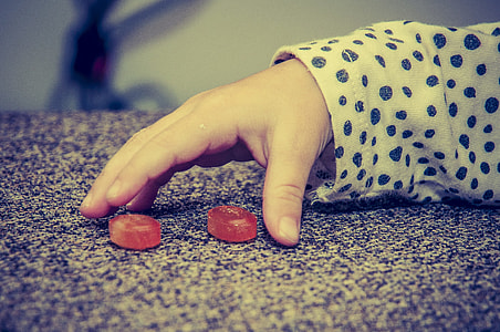 close-up photo of toddler's right human hand beside two red plastic ornaments thumbnail