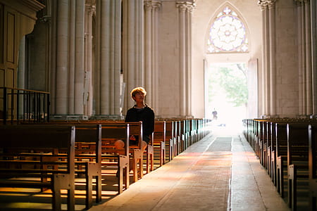 man sitting on pew near wall thumbnail