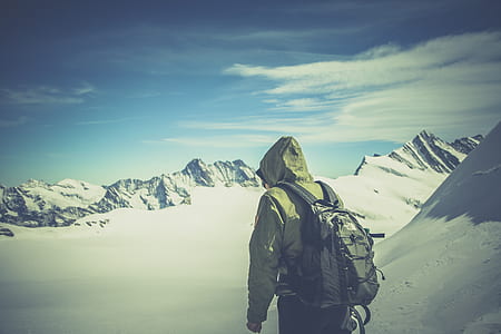 person in brown hoodie carrying black backpack on field cover by snow during daytime thumbnail