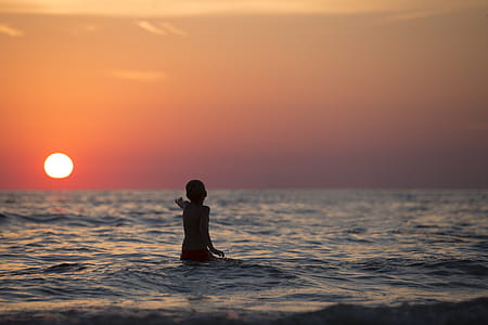 Boy in Ocean during Golden Hour thumbnail