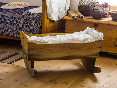 photo of brown wooden rocking bassinet beside bed thumbnail