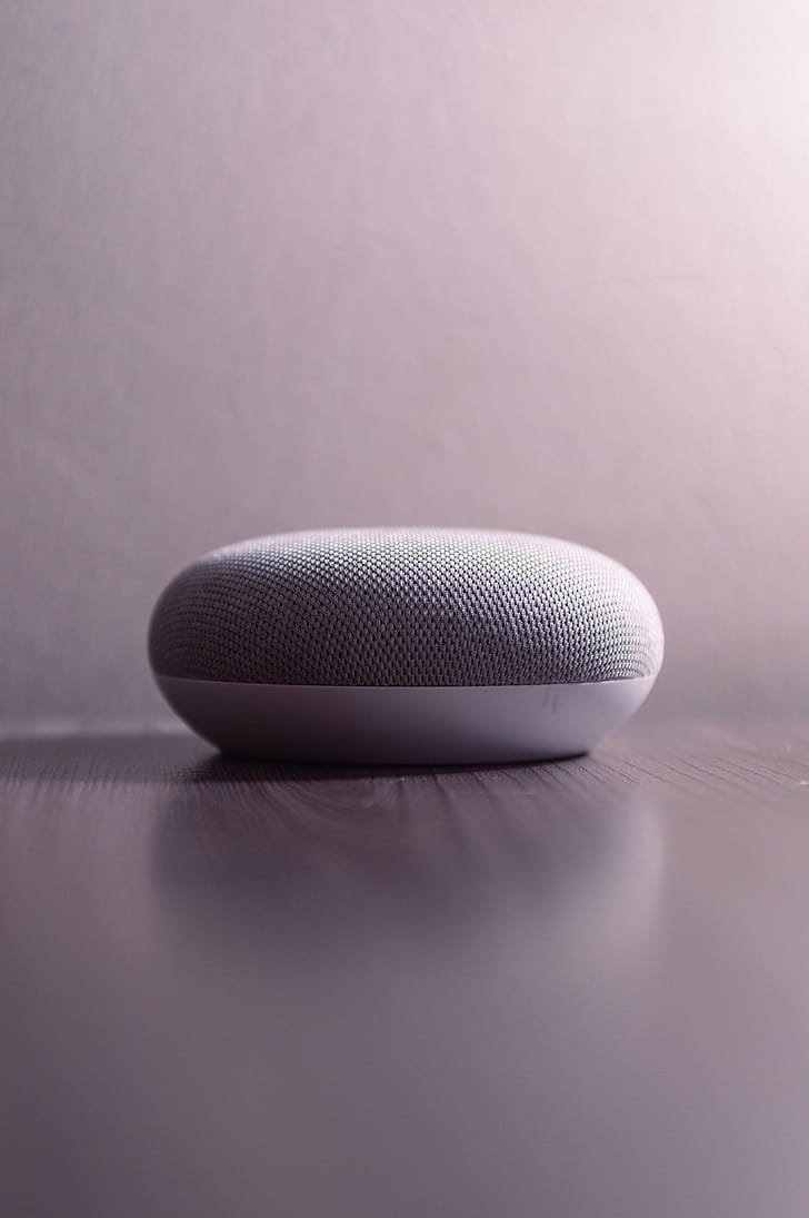 White and Gray Bluetooth Speaker on Brown Wooden Surface