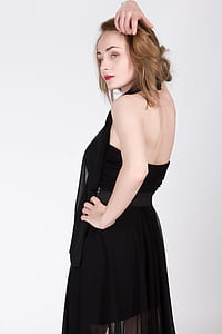 woman in black dress standing near white painted wall thumbnail