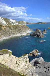 rocky cliff under white and blue cloudy skies thumbnail