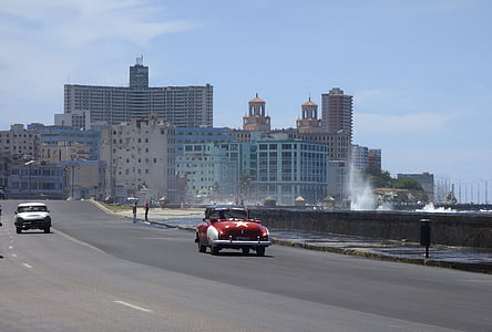 classic red traveling on road near buildings during daytime thumbnail
