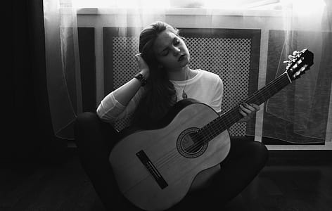 Greyscale Photography of Woman in Crew Neck Long Sleeve Shirt Holding Guitar thumbnail