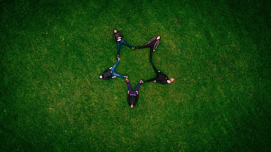 five people forming a star while lying on grass field thumbnail