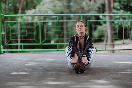 Blonde woman in a black jacket and ripped jeans by a green handrail thumbnail