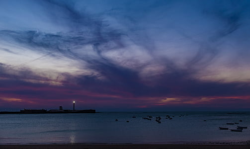 island with lighthouse with its light during dusk thumbnail