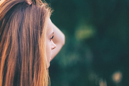 selective focus photography of woman holding her own hair thumbnail