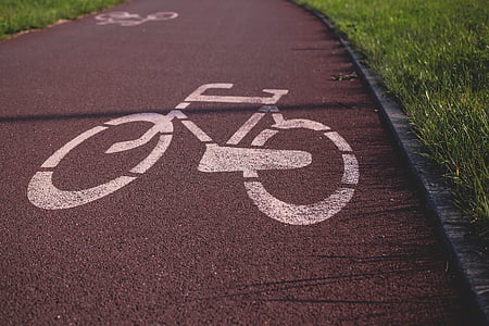 white bicycle lane near grass field during daytime thumbnail
