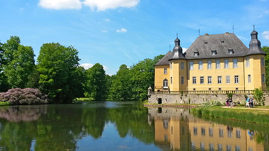 yellow and gray gothic building beside lake thumbnail