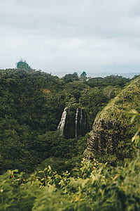 green mountain covered in green leafed plants under cloudy sky thumbnail