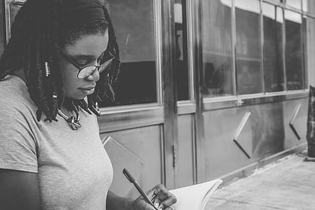 grayscale photo of woman holding pen thumbnail