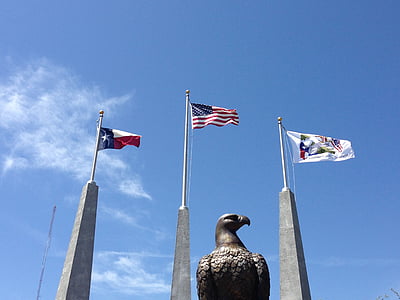 three assorted flags waving under clear blue sky thumbnail