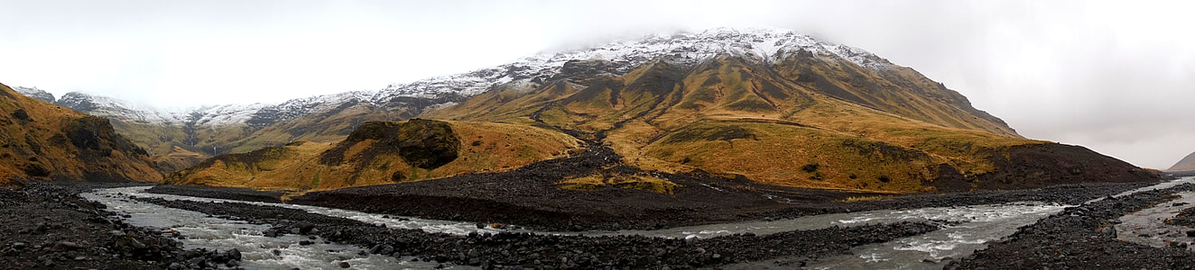 brown mountain near river during daytime thumbnail