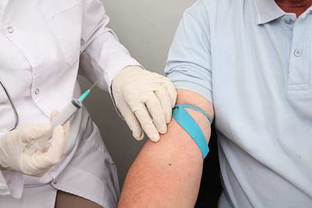 person holding clear plastic syringe beside white wall thumbnail