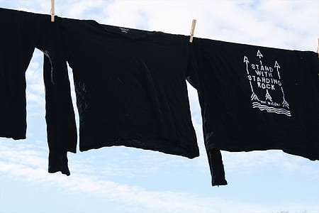 three black shirts hanging under blue sky thumbnail