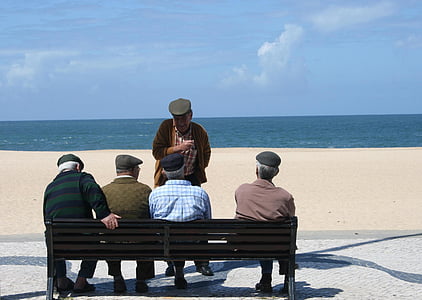 man standing infront of four men sitting on bench during daytime thumbnail