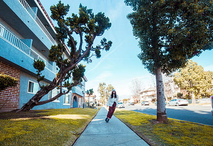 woman walking on concrete sidewalk beside tree thumbnail