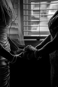 grayscale photography of woman wearing wedding gown holding the hands of woman thumbnail
