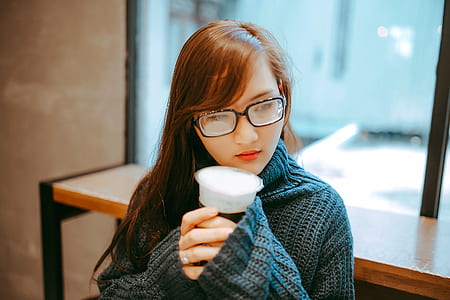 woman holding coffee cup inside well-lighted room thumbnail