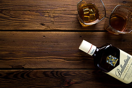 black Ballantine's Finest bottle on brown wooden pallet surface beside tow drinking glasses filled with brown liquid thumbnail