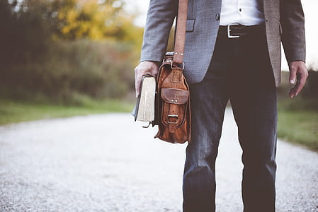 man walking at pathway while holding book thumbnail