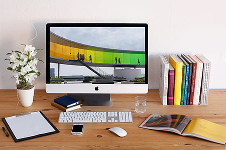 turned-on iMac beside books on desk thumbnail