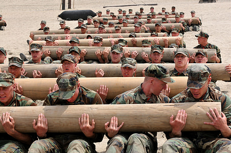 soldier holding tree log during daytime thumbnail