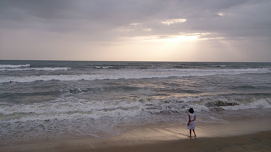 woman stands on seashore front of seawaves at daytime thumbnail