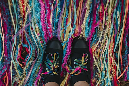 person showing pair of black sneakers on multicolored strings thumbnail