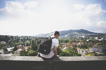 man in white T-shirt sitting on concrete wall thumbnail