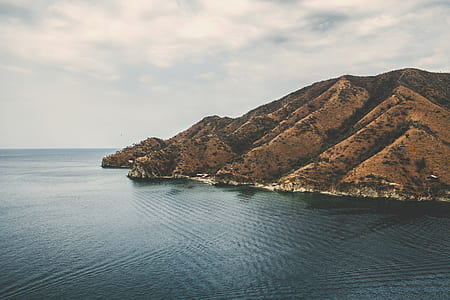 brown mountains surrounded by body of water thumbnail