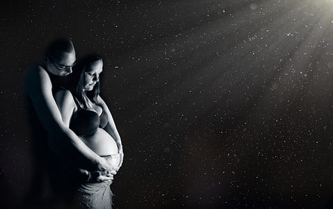 grayscale photography of man and pregnant woman touching baby bump thumbnail