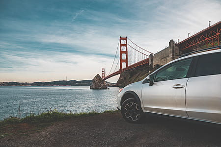 silver car near suspension bridge and body of water thumbnail