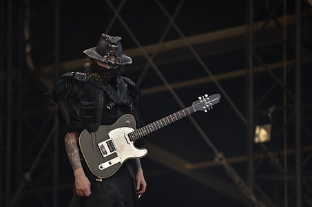 person carrying black electric guitar while standing on stage thumbnail
