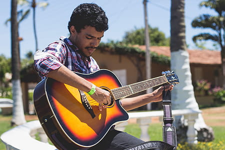 Man Holding Guitar Near Tree thumbnail