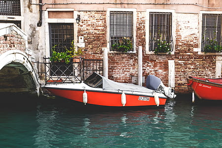 red and white speedboat on body of water beside concrete building thumbnail