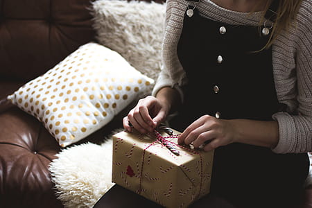 woman sitting on white sofa with brown present box on lap thumbnail