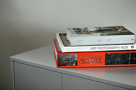 three assorted books on gray side board thumbnail