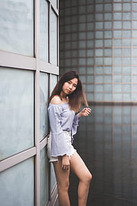 woman wearing blue off-shoulder blouse leaning on wall during daytime thumbnail