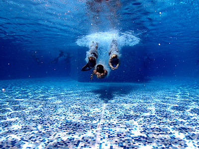 underwater photography of three person swimming underwater thumbnail