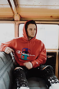 man wearing red Champion pullover hoodie sitting on black backseat inside the vehicle thumbnail