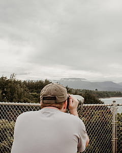 person viewing body of water and mountains from coin-operated telescope thumbnail