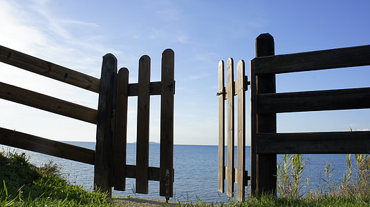 brown wooden gate opened near seashore at daytime thumbnail
