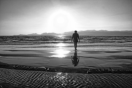 grayscale photo of person walking towards sea thumbnail