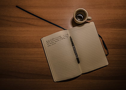 ballpoint pen on white lined paper near coffee mug on brown wooden table thumbnail